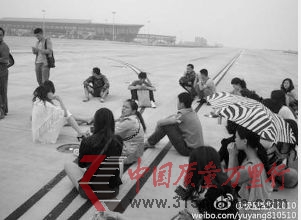 網(wǎng)友@極品寶貝2010在微博上貼出乘客圍坐機場跑道的照片